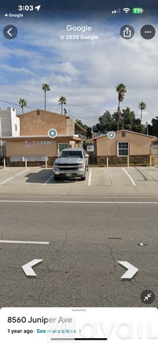 A car is parked in a parking lot with a building and palm trees in the background.