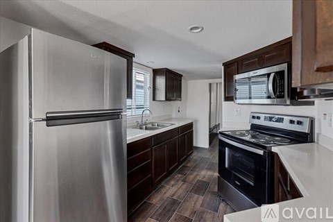 A modern kitchen with a stainless steel refrigerator and dark wood cabinets.