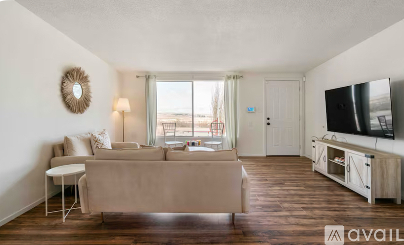 A living room with a couch, a chair, a television, and a window with a view of the beach.