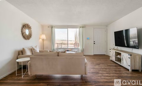 A living room with a couch, a chair, a television, and a window with a view of the beach.