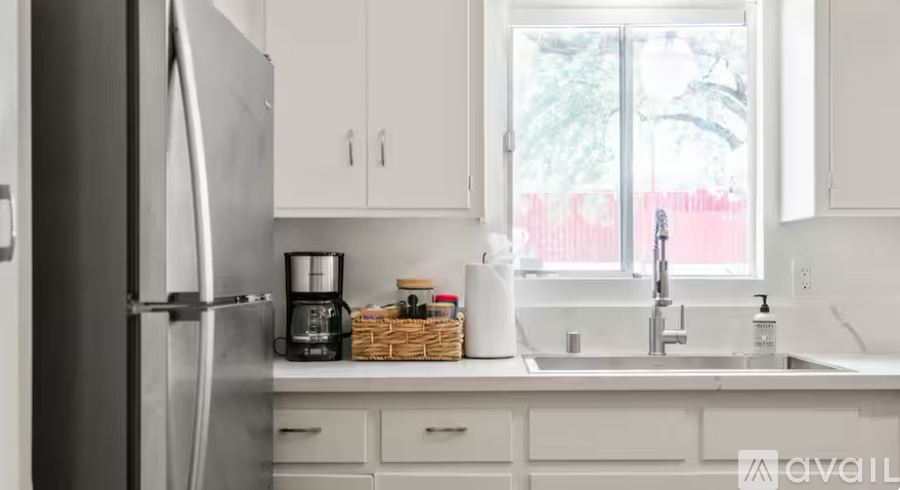 A kitchen with a refrigerator, sink, and window.