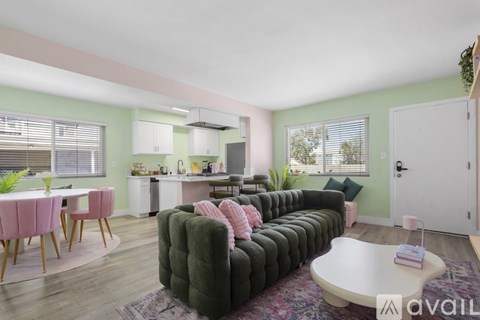 A living room with a green couch and pink chairs.