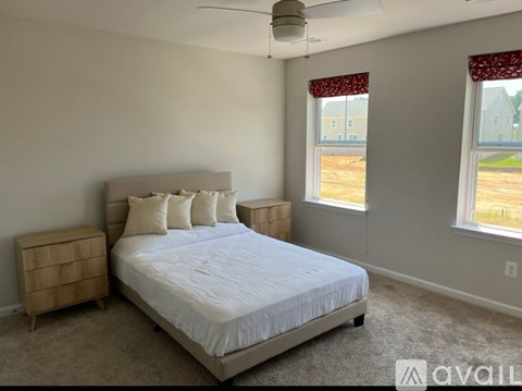 A bedroom with a large bed and a window with red curtains.