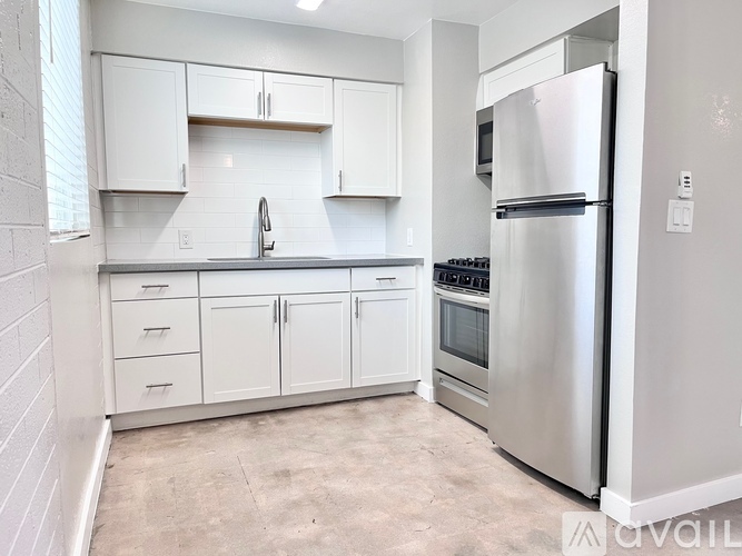 A kitchen with white cabinets and a stainless steel refrigerator.
