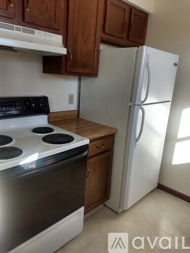 A kitchen with a white stove top oven and a white refrigerator.