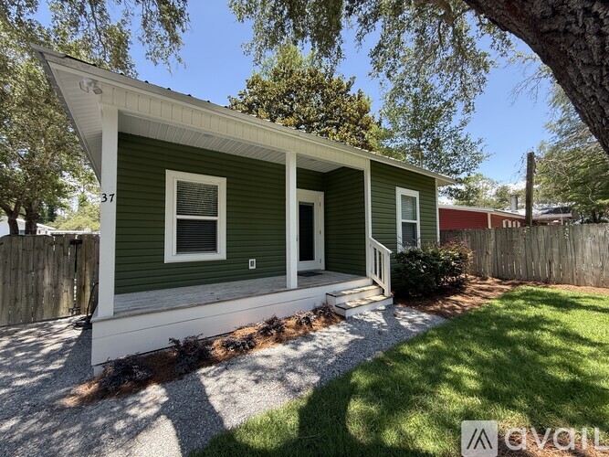 A green house with a white trim and a porch.