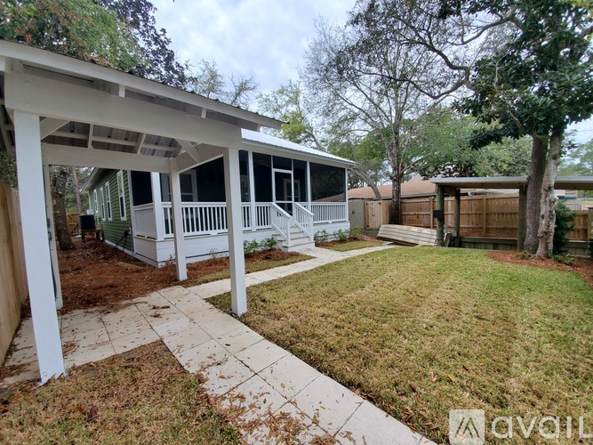 A covered patio area with a white pergola and a concrete walkway leading to a house.