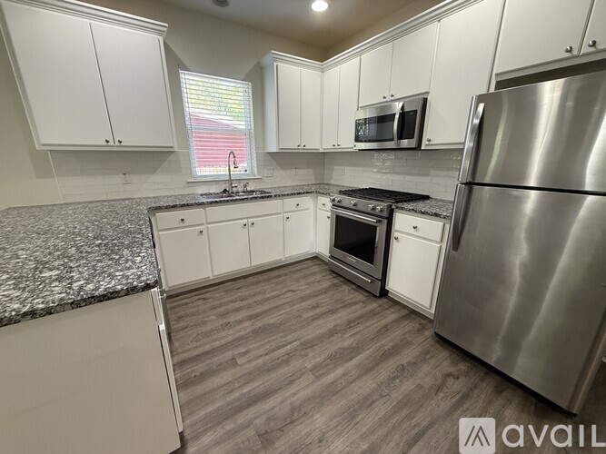 A kitchen with white cabinets and a granite countertop.