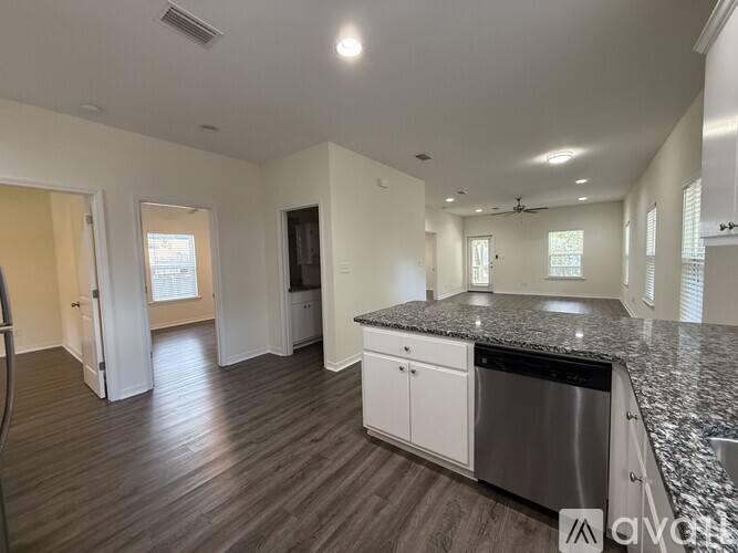 A spacious room with a ceiling fan and three windows.
