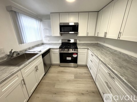 A kitchen with white cabinets and a black stove top oven.