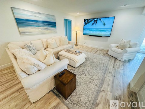 A living room with a large painting and a flat screen TV mounted on the wall.
