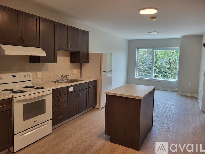 A kitchen with dark brown cabinets and white appliances.