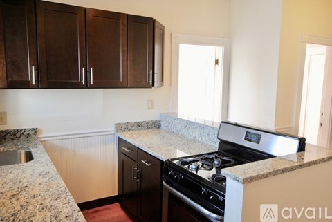 A kitchen with granite countertops and dark brown cabinets.