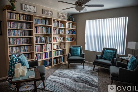 A living room with a bookshelf filled with books and a sign that says "Blessed" on the wall.