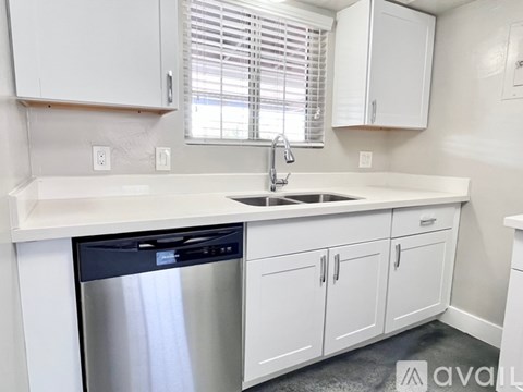 A kitchen with white cabinets and a stainless steel dishwasher.
