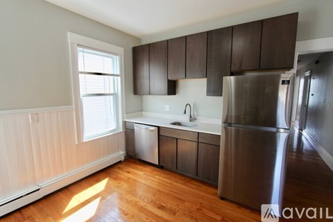 A kitchen with wooden floors and a stainless steel refrigerator.