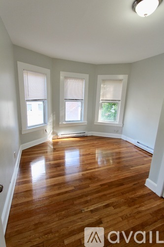 A room with wooden floors and three windows.