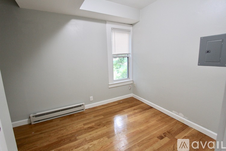 A room with wooden flooring and a window with blinds.