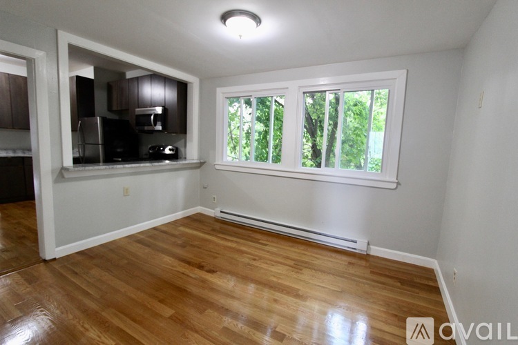 A room with wooden floors and a window overlooking trees.