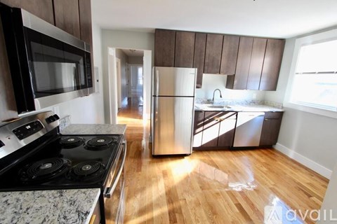 A kitchen with a black stove top oven and a stainless steel refrigerator.