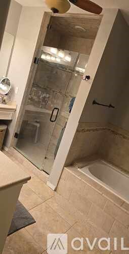 A bathroom with a glass shower door and a fan.