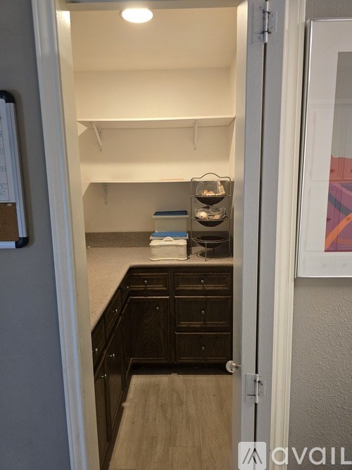 A small kitchen with a refrigerator on the left and a door open to a hallway.
