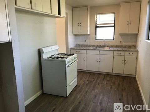 A kitchen with a white stove and cabinets.