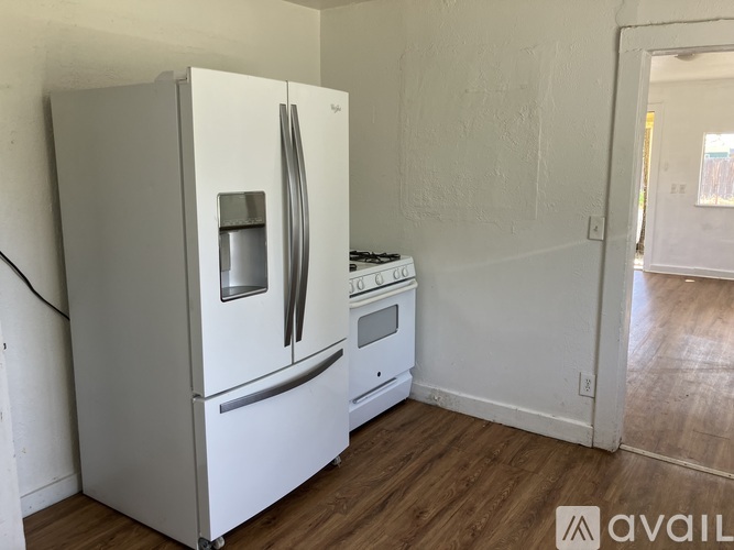 A white refrigerator and stove in a kitchen with wood flooring.