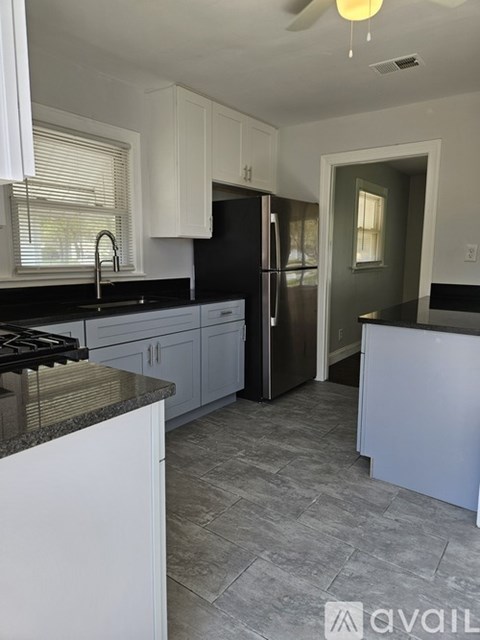 A kitchen with a black fridge and a white countertop.