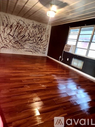 A room with wooden flooring and a large abstract painting on the wall.