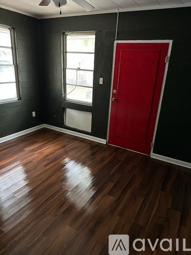 A room with a red door and wooden flooring.