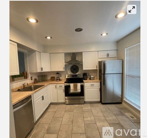 A kitchen with white cabinets and a stainless steel refrigerator.