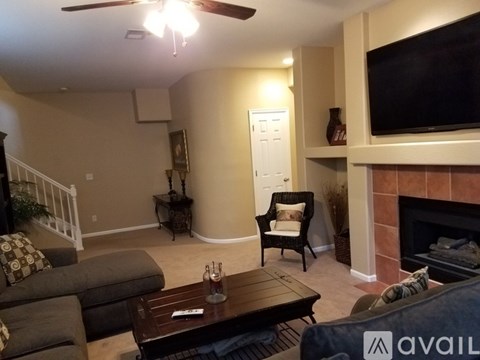 A living room with a grey couch, a wooden coffee table, and a television mounted on the wall.