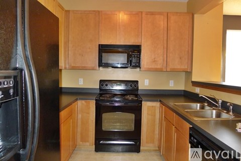 A kitchen with wooden cabinets and black appliances.