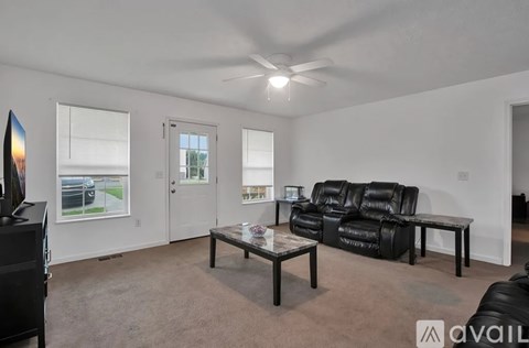 A living room with a black leather couch and a glass coffee table.