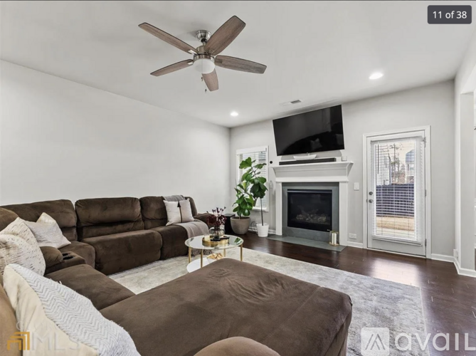 A living room with a brown couch and a white ceiling fan.