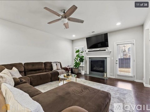 A living room with a brown couch and a white ceiling fan.