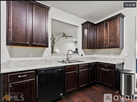 A kitchen with dark brown cabinets and a white counter top.