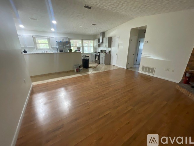 A spacious room with wooden flooring and white walls.