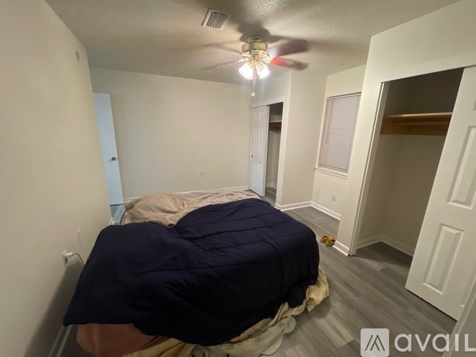 A bedroom with a bed covered in a blue blanket and a ceiling fan with lights.