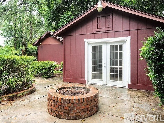 A red building with a white door and a brick fire pit in front.