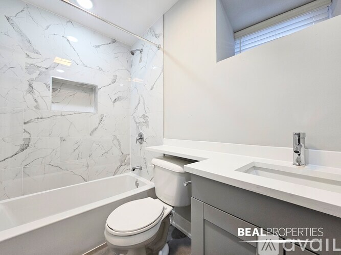 A white toilet sits next to a marble wall in a bathroom.