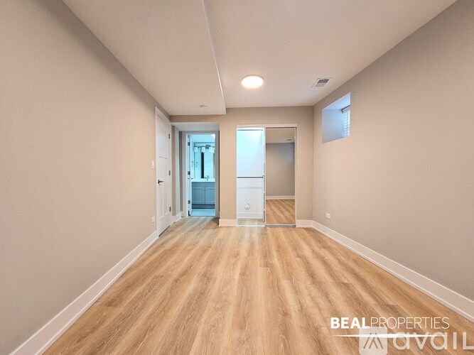A spacious room with wooden flooring and a doorway leading to another room.