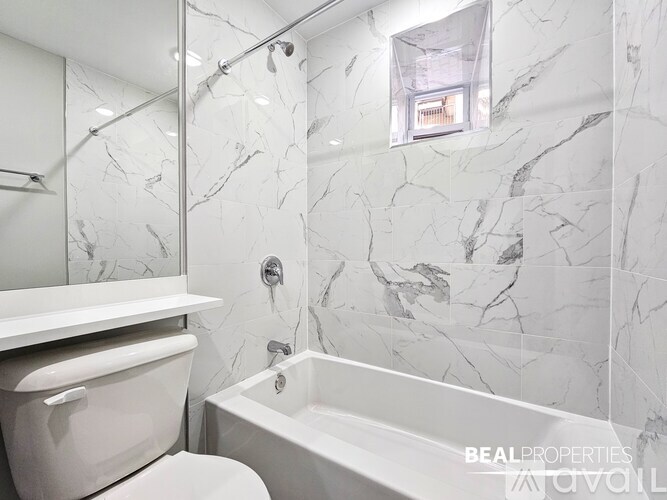A white bathroom with a marble wall and a white bathtub.