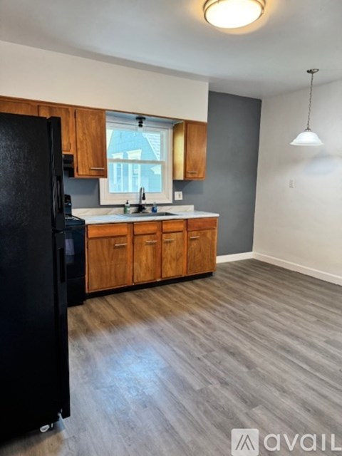 A kitchen with wooden cabinets and a black refrigerator.