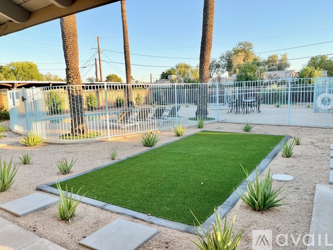 A small grassy area surrounded by a fence and concrete blocks.