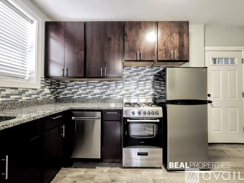 A kitchen with dark wood cabinets and a stainless steel refrigerator.
