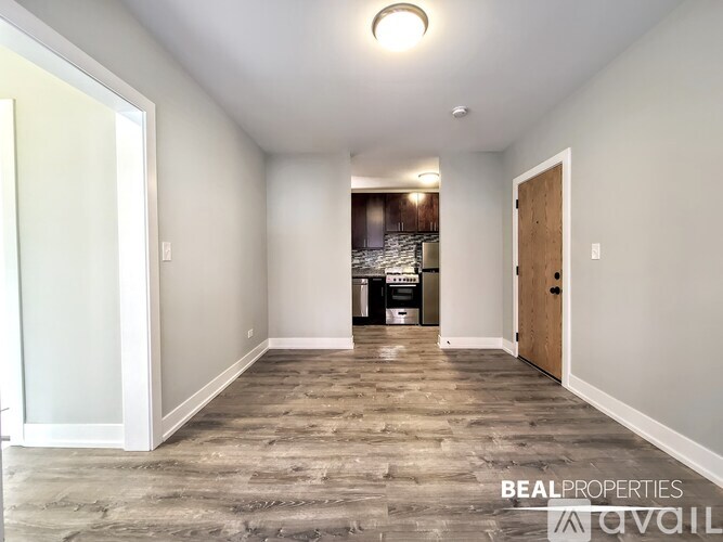 A spacious room with wooden flooring and a door on the right.