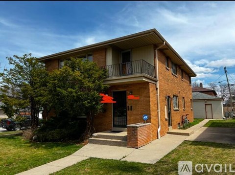 A two-story brick house with a balcony on the second floor.