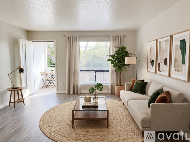 A living room with a couch, a coffee table, and a window with a view of the outdoors.